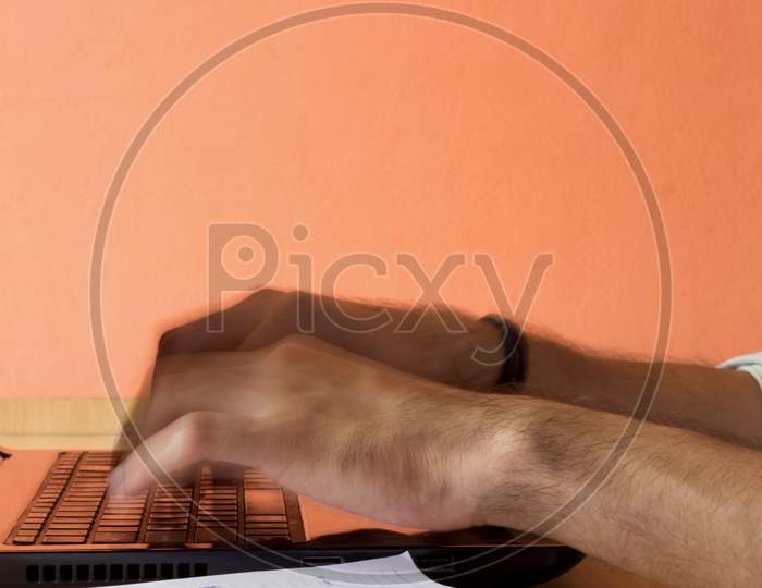 A male person typing on a Laptop