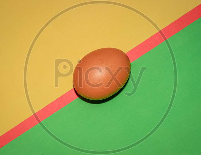 Brown colour egg on  yellow,red and green colour background . Top view.