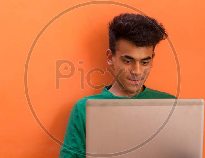 A Young Man Smiling While Talking To Someone On His Laptop