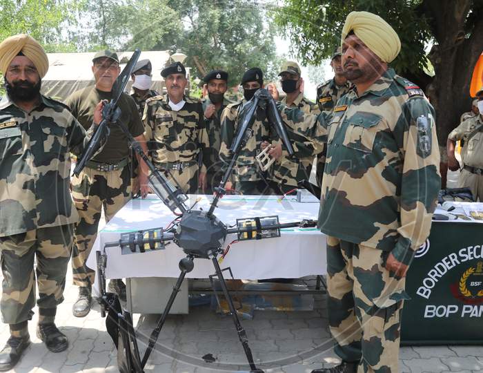 BSF personnel with Pakistani drone which it's troops shot down along the International border in Kathua district of Jammu and Kashmir on Saturday. A cache of arms and explosives including US made M4 semi automatic carbine machine and seven grenades were recovered, frustrating Pakistani attempt to sm
