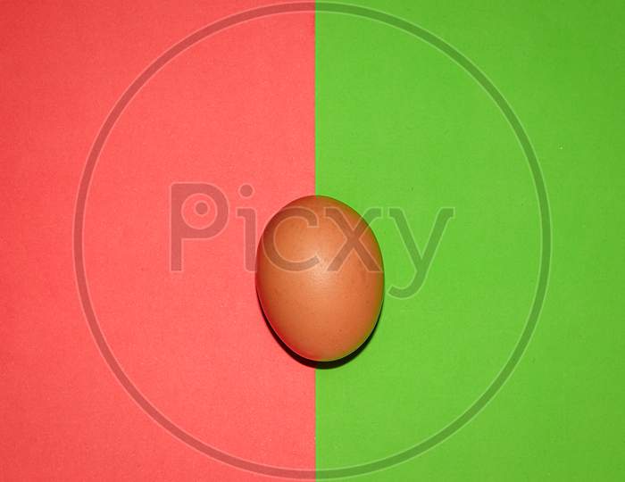 Brown colour egg on red green  two colour background . Top view.