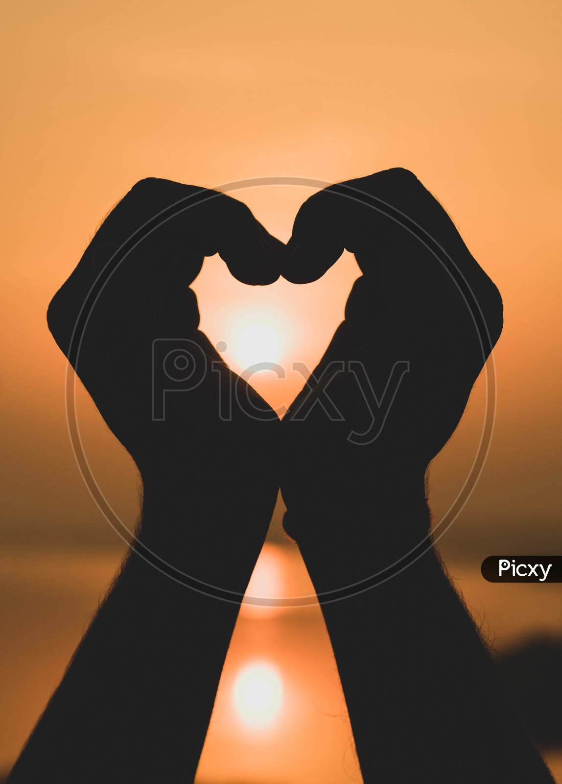 Hands Forming A Heart Shape With Sunset Silhouette.