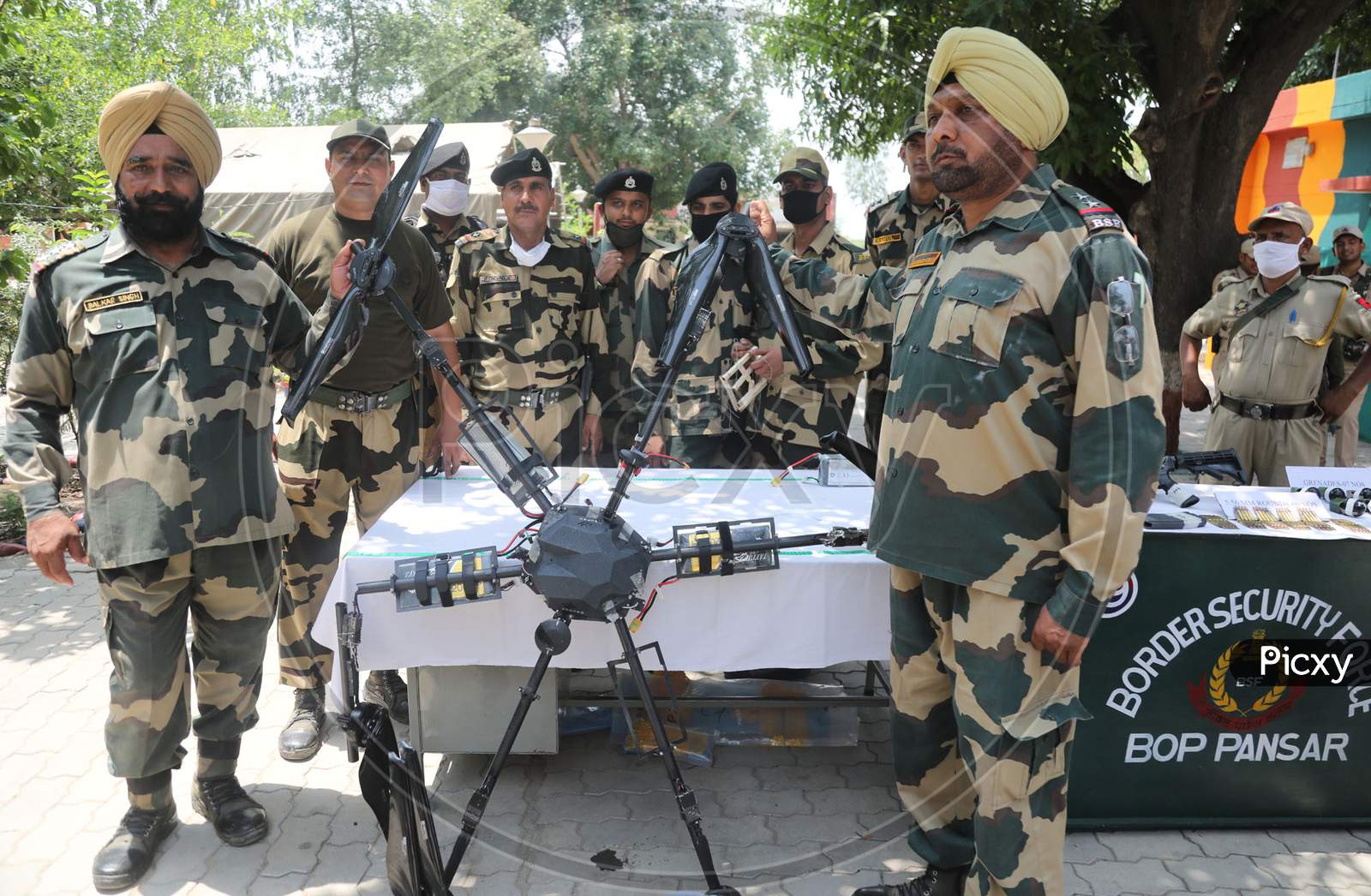 BSF personnel with Pakistani drone which it's troops shot down along the International border in Kathua district of Jammu and Kashmir on Saturday. A cache of arms and explosives including US made M4 semi automatic carbine machine and seven grenades were recovered, frustrating Pakistani attempt to sm