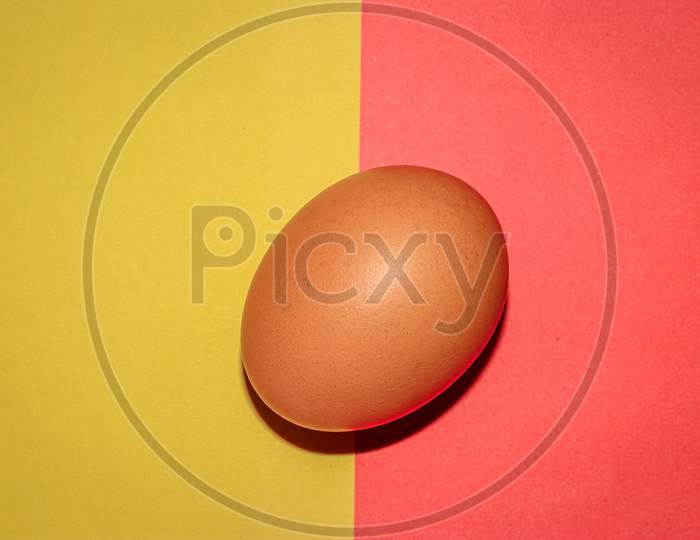 Brown colour  egg on yellow red two colour background . Top view.