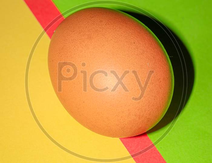 Brown colour egg closeup on yellow,red and green  colour background . Top view.