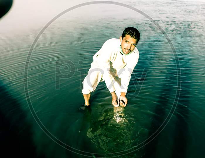 A young man is playing with river water.
