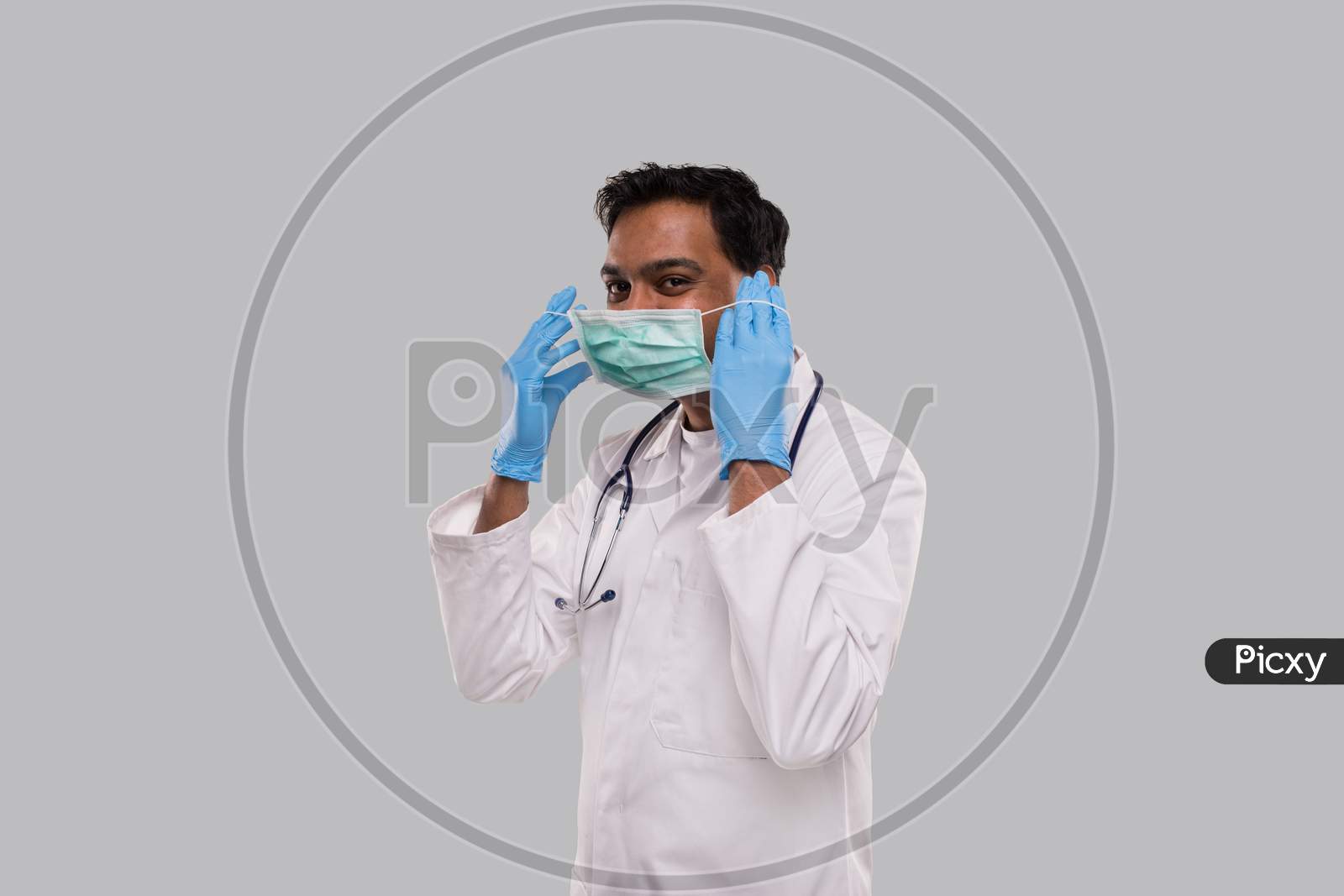 Doctor Puts On Medical Mask Wearing Gloves Isolated. Indian Man Doctor Medical Uniform