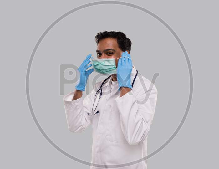 Doctor Puts On Medical Mask Wearing Gloves Isolated. Indian Man Doctor Medical Uniform