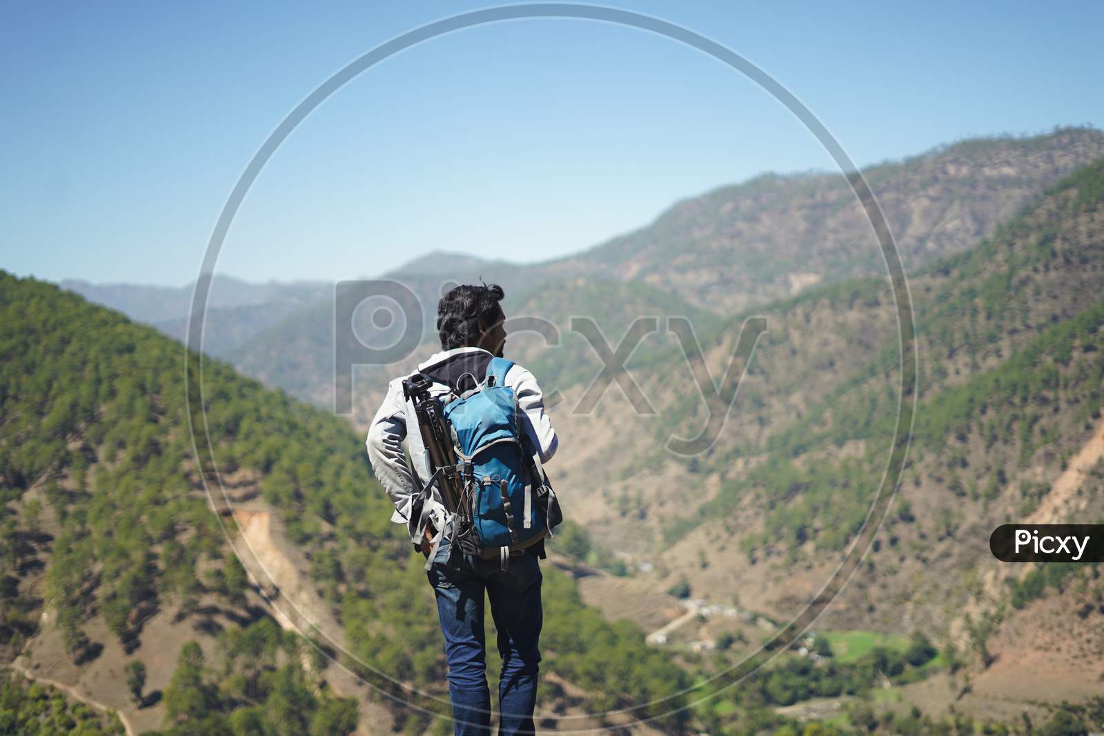 Young Handsome Indian Boy Standing On The Top Of The Mountain With A Bag Pack , Traveling And Wanderlust.