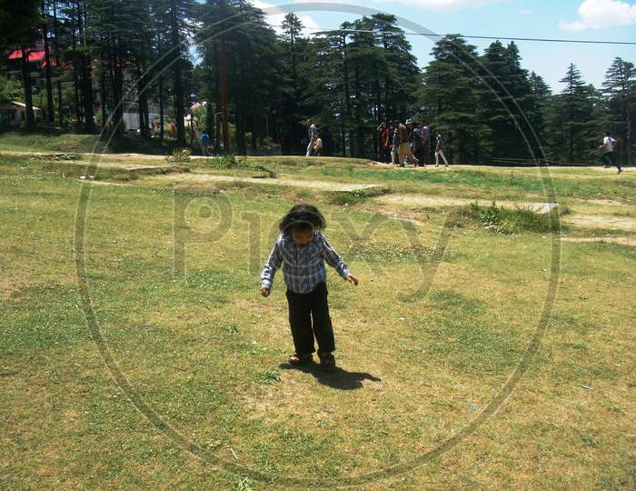 child observing his shadow in the green meadow of Patnitop