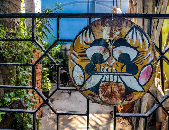Clay Decorative Hanging On Iron Gate. Also Called As Drishti Bommai.Colorful Demon Face Of Drishti Bommai Talisman To Ward Off Evil Forces In Front Of A House