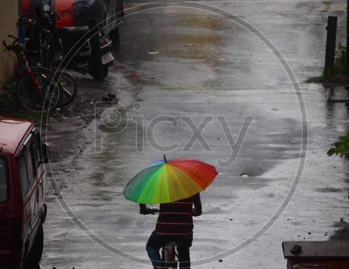 Boy riding bicycle in rain and holding umbrella