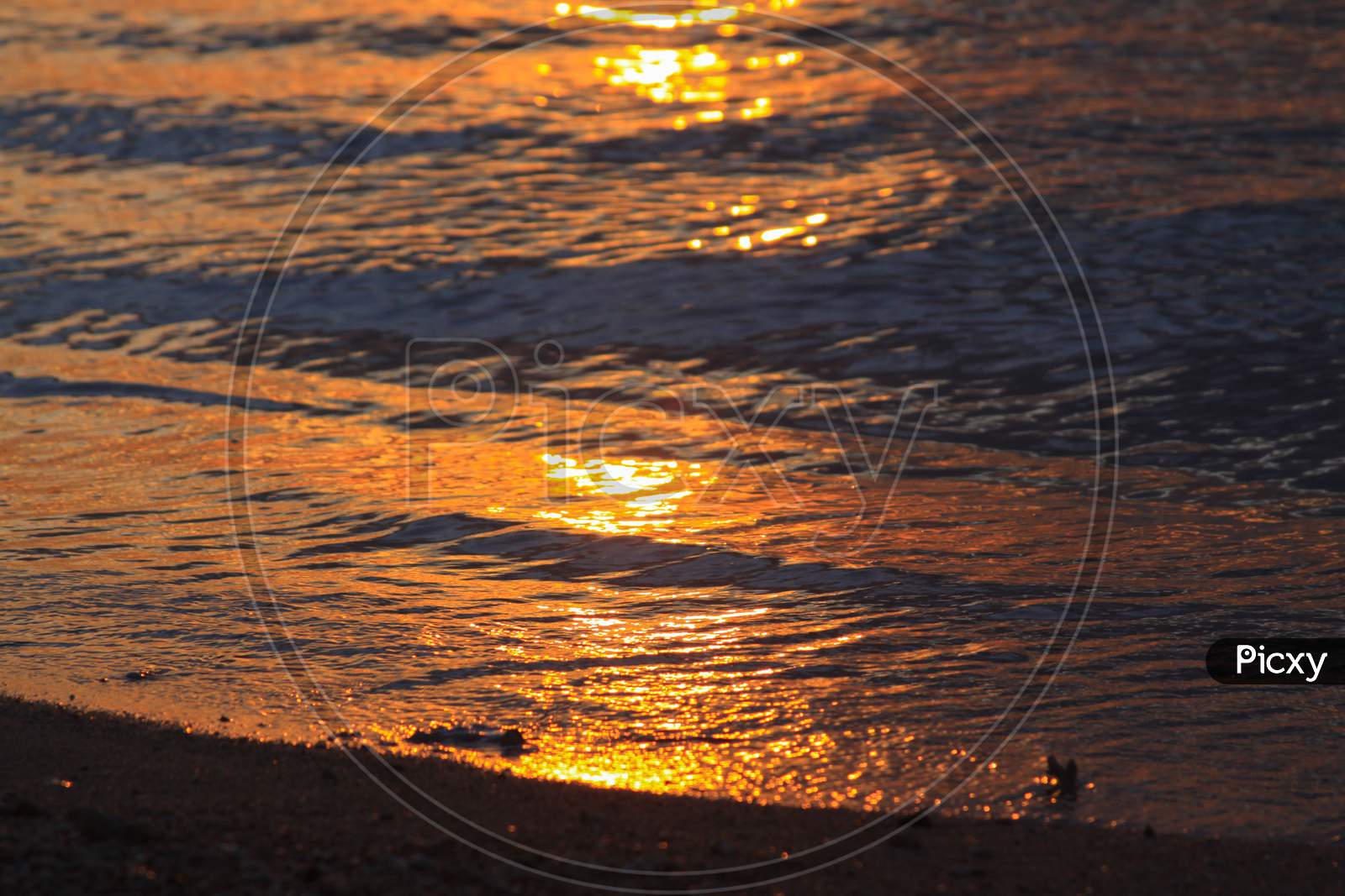 Sun Light Reflected In Waves On Beach At Sunset