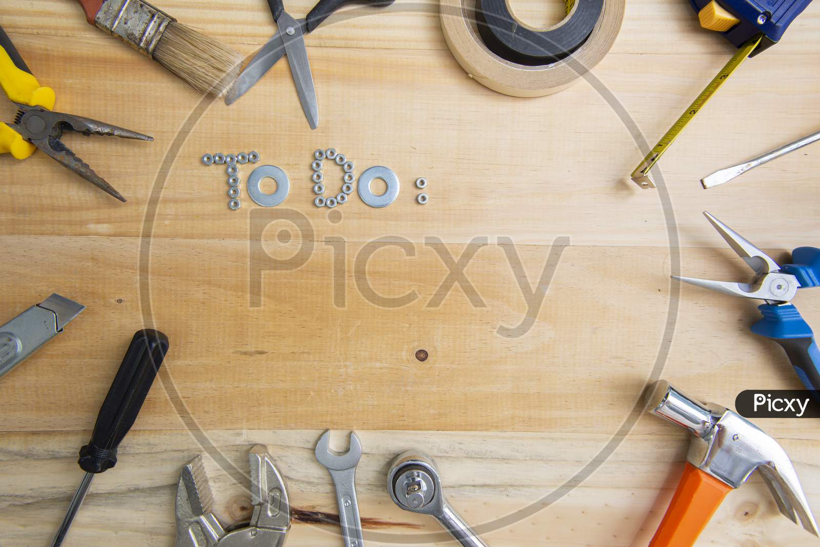 A High Angle Shot Of The Phrase "To Do" Made Of Screws Surrounded By Instruments On A Wooden Surface For Planning The Work