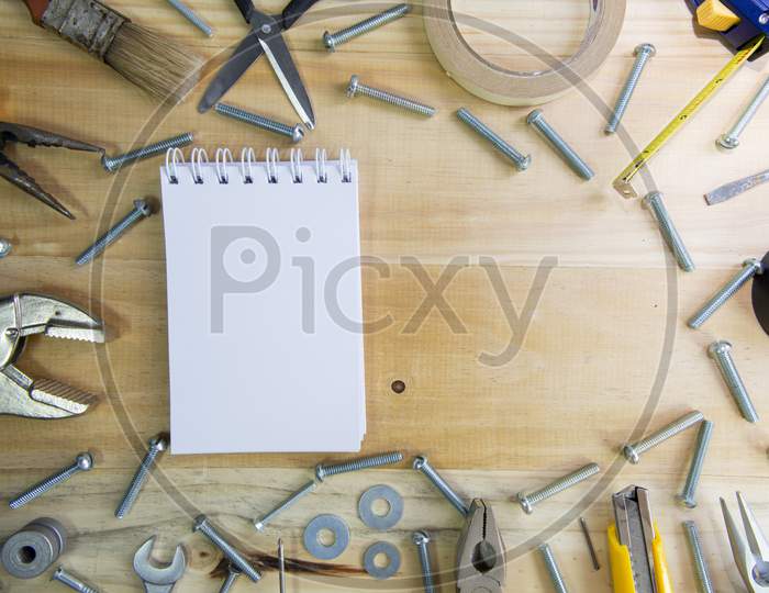 A Blank Notebook With Space For Text Surrounded By Instruments On A Wooden Surface. Construction Tools Framing Wooden Background Shot From Above.