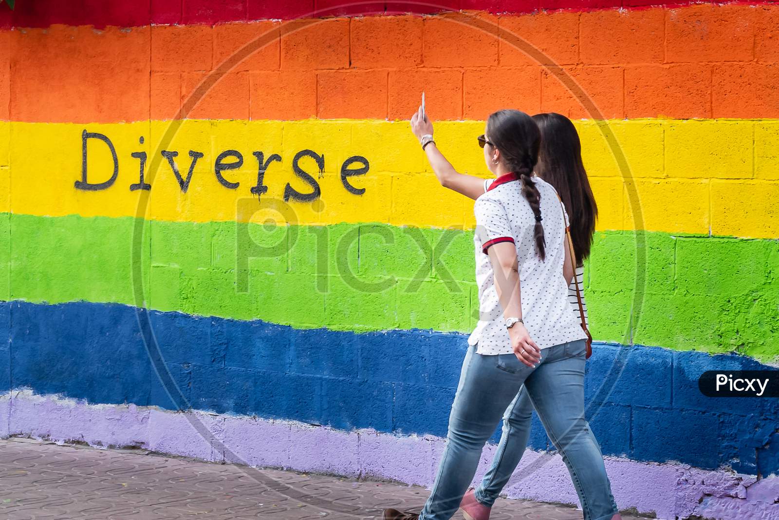 Wall With The Colors Of The Lgbt Flag And Two Women Walking Together
