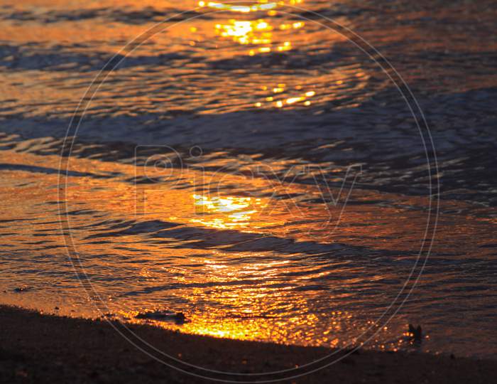 Sun Light Reflected In Waves On Beach At Sunset
