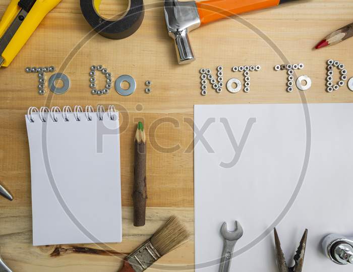 Top View Of The Phrases "To Do" And "Not To Do" Made Of Nuts And Washers On A Wooden Surface For Planning The Work. Construction Tools Framing Wooden Background Shot From Above.
