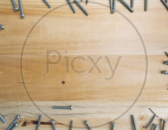 Screws Scattered On A Wooden Surface With A Space For Text In The Center