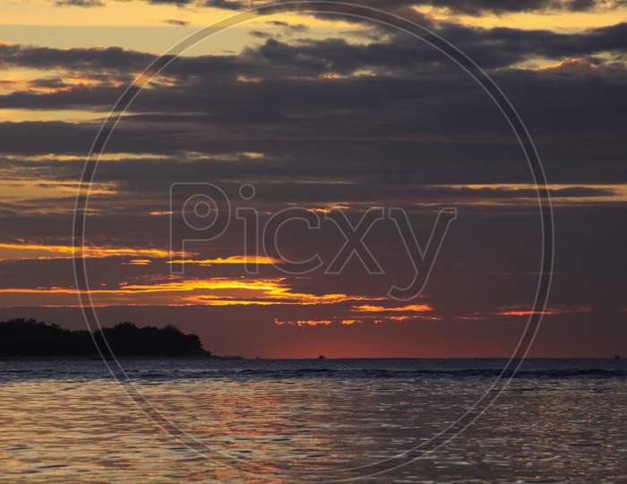 Sun Behind Clouds With Exotic Island Silhouette