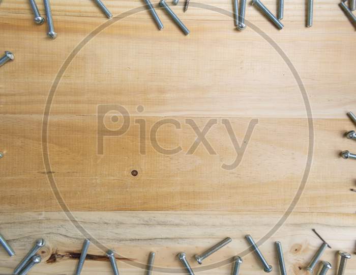 Screws Scattered On A Wooden Surface With A Space For Text In The Center