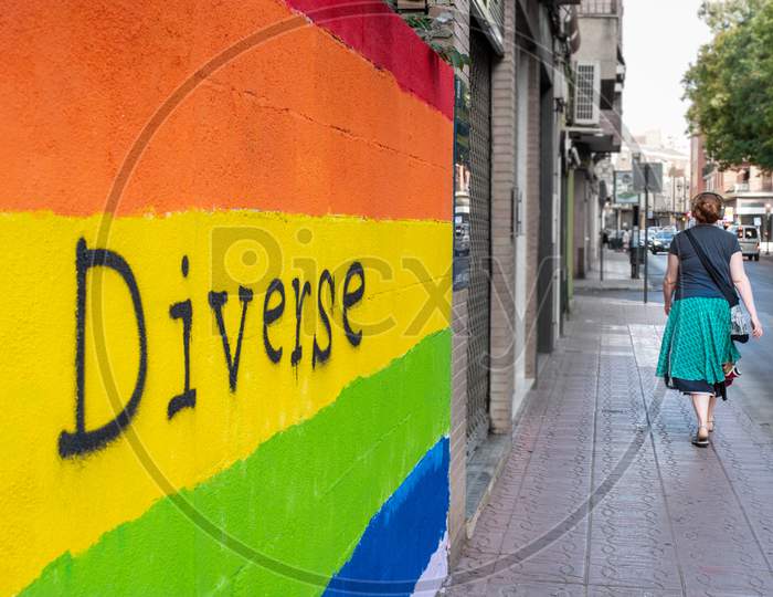 Wall With The Colors Of The Lgbt Flag And Woman Walking And Listening Music