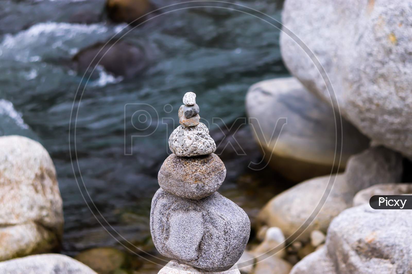 Rock Balancing Having Flowing River In The Background