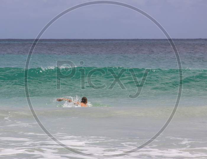 Swimmer In Ocean Waves At Mawun Beach Lombok, Indonesia