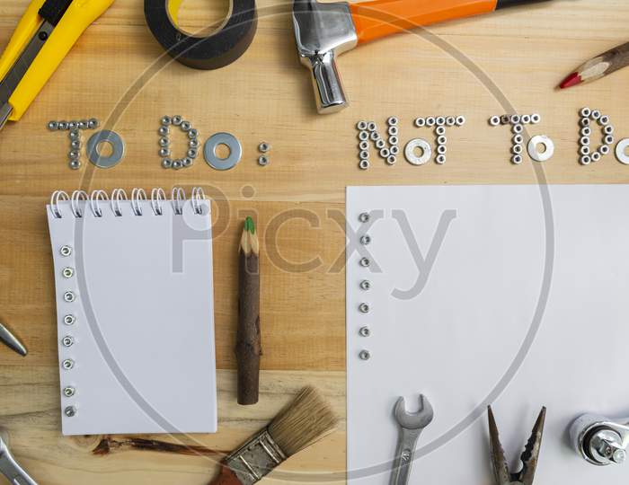 Top View Of The Phrases "To Do" And "Not To Do" Made Of Nuts And Washers On A Wooden Surface For Planning The Work. Construction Tools Framing Wooden Background Shot From Above.