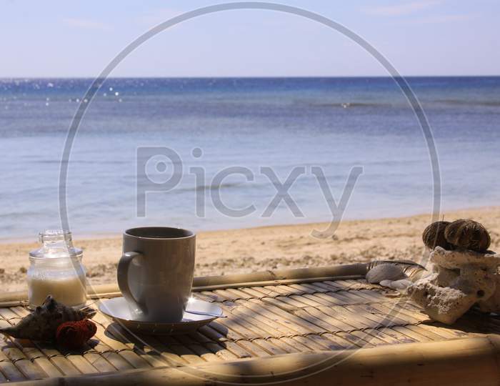Coffee, Sugar, Shell And Coral On Table On Beach