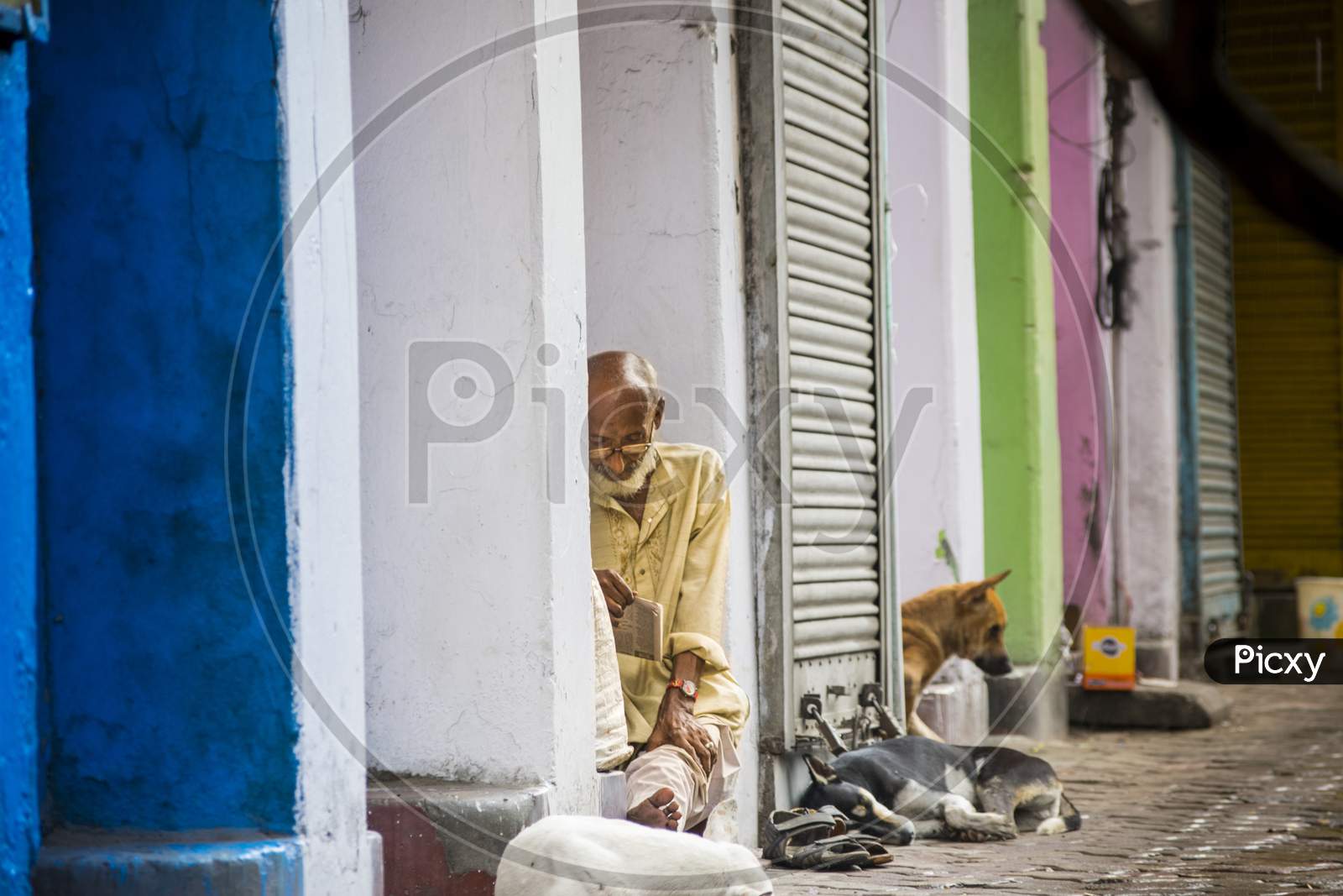 A homeless old person sitting on footpath while raining in kolkata