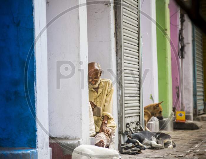 A homeless old person sitting on footpath while raining in kolkata