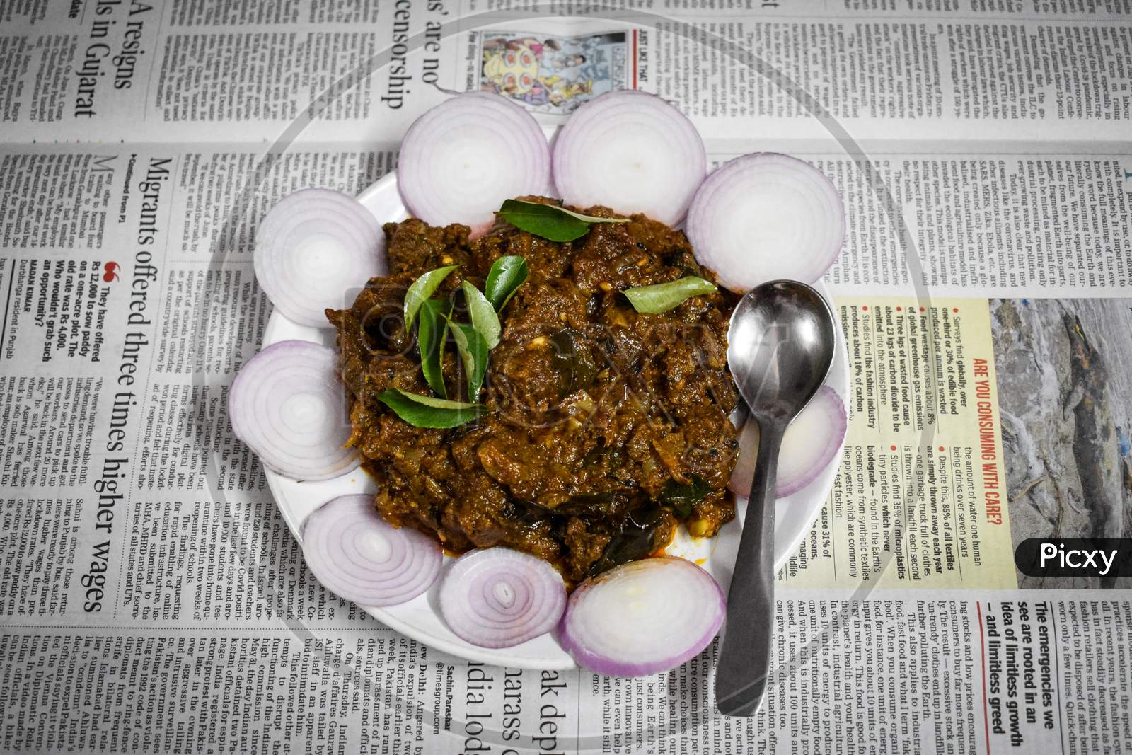 06/06/2020-Kerala, India: South Indian Cuisine Kerala Style Beef Fry / Roast. Traditional Style Meat Roast. Garnished With Onion Slices And Curry Leaves On Newspaper Background.