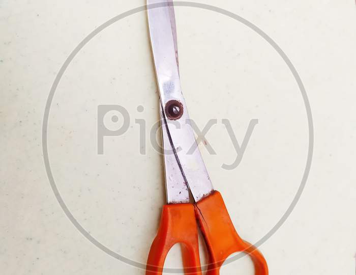 Topview of orange scissor isolated on white surface, the scissors use for tailoring uses