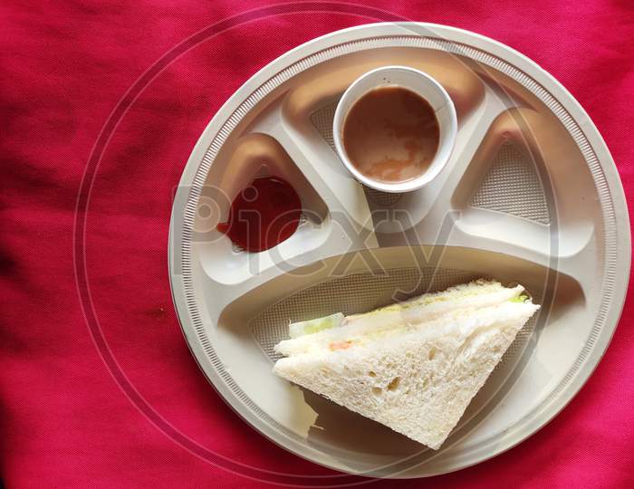 Top view: Sandwiches with tomato sauce and a cup of tea in the plate in breakfast
