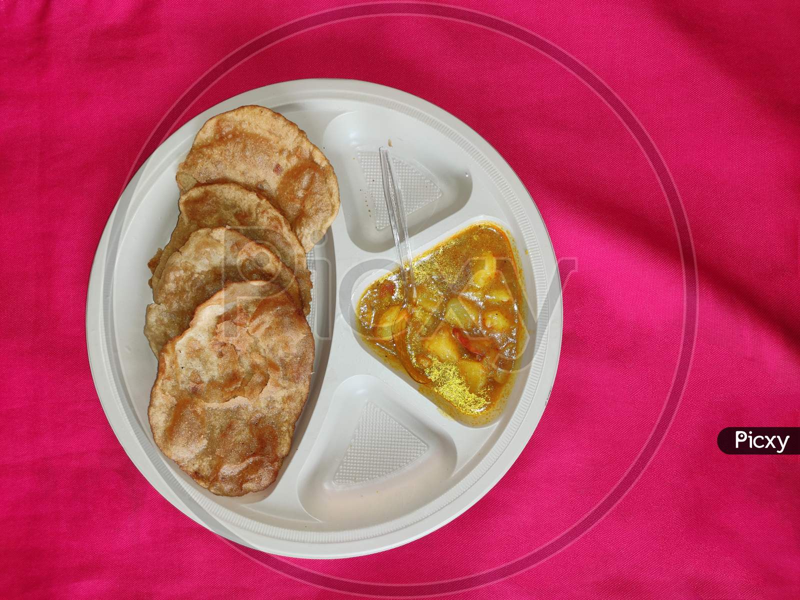 Top view: Puri and Potato Curry aalu sabji - an indian cuisine in round plate.