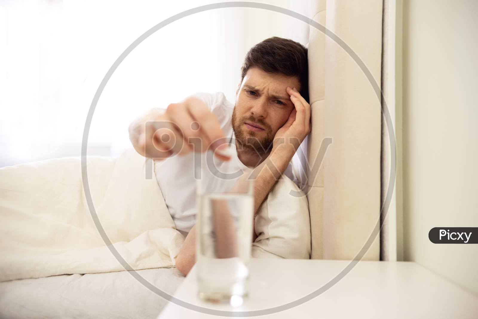 Hangover. Man Puts Pill In Water. Man In Bed Morning Headache. Man Using Aspirin. Glass Of Water Close Up.