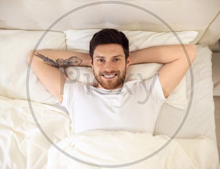 Handsome Man Laying In Bed Smiling. Morning At Home. Up Down Shoot. Man Portrait In Bed Watching In Camera.