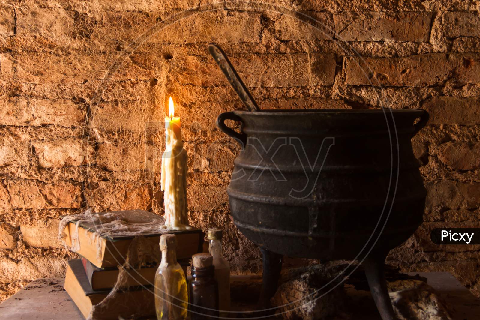Spell Of Witch Night With Candles And Pot With Fire Between Cobwebs And Ancient Earth