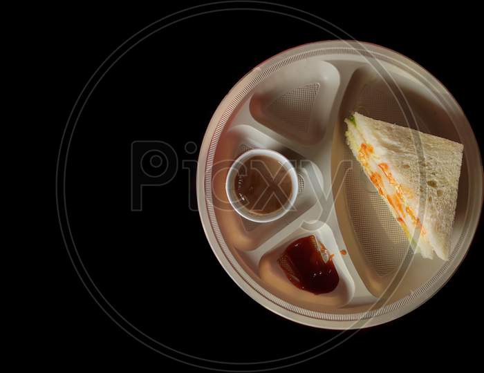 Two halves of fresh club sandwich with tea on white plate on black  background isolated.