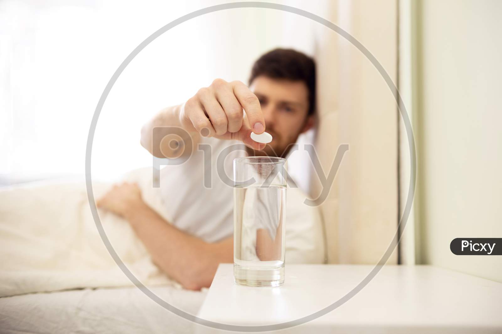 Hangover. Man Puts Pill In Water. Man In Bed Morning Headache. Man Using Aspirin. Glass Of Water Close Up.
