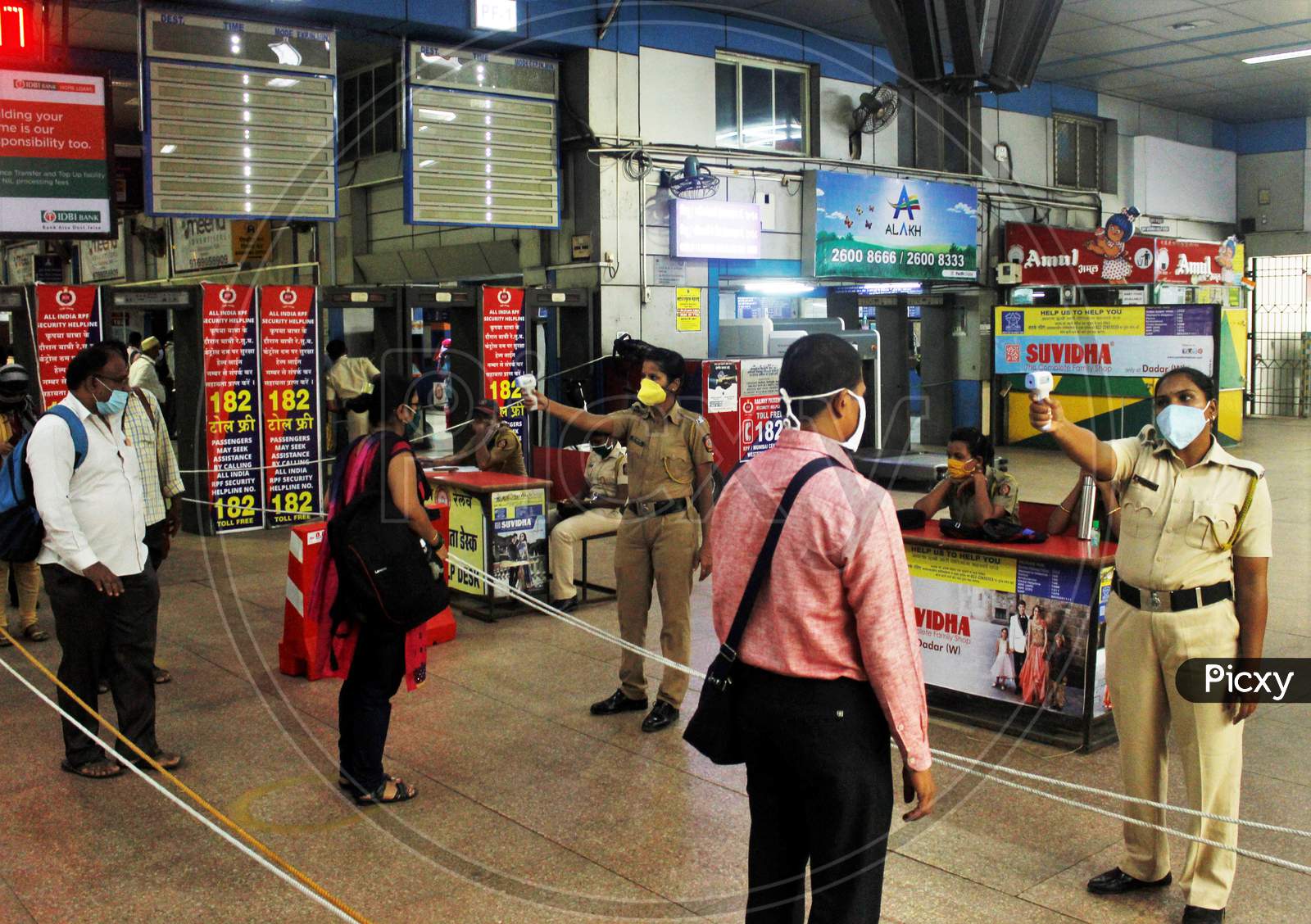 Police personnel check the temperature of the essential service workers going to board the train,  after the government eased a nationwide lockdown that was imposed as a preventive measure against the COVID-19 coronavirus, at Churchgate station, in Mumbai, India, on June 16, 2020.
