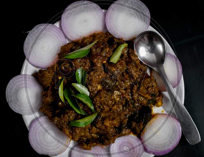 South Indian Cuisine Kerala Style Beef Fry / Roast. Traditional Style Meat Roast. Garnished With Onion Slices And Curry Leaves. Black Background. Selective Focus Photograph.