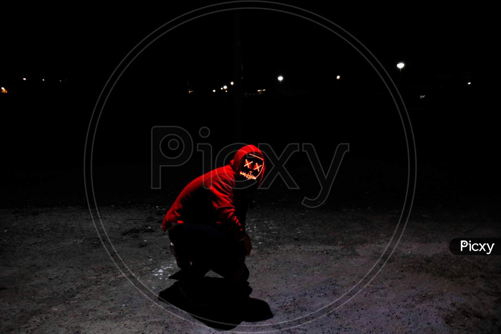 A Man Wearing A Red Hoodie With Red Glowing Mask Sitting On The Ground.
