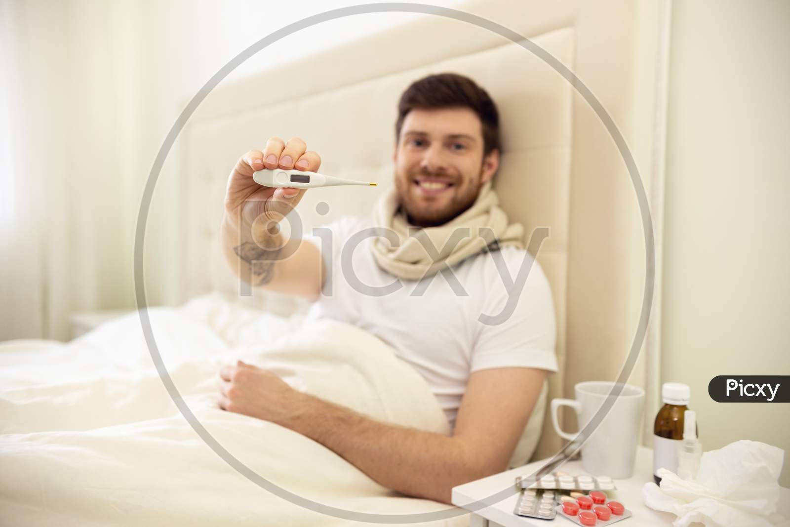Man Sick In Bed Showing Thermometer, Smiling. Man Having Good Temperature. Man Ill At Home.