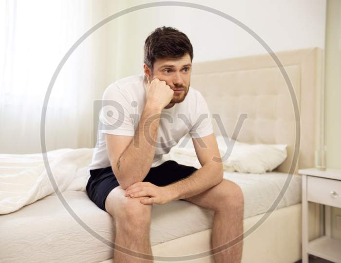 Man Sitting On Bed Tired. Disappointed Man At Home. Lonely Bored Man In Bed
