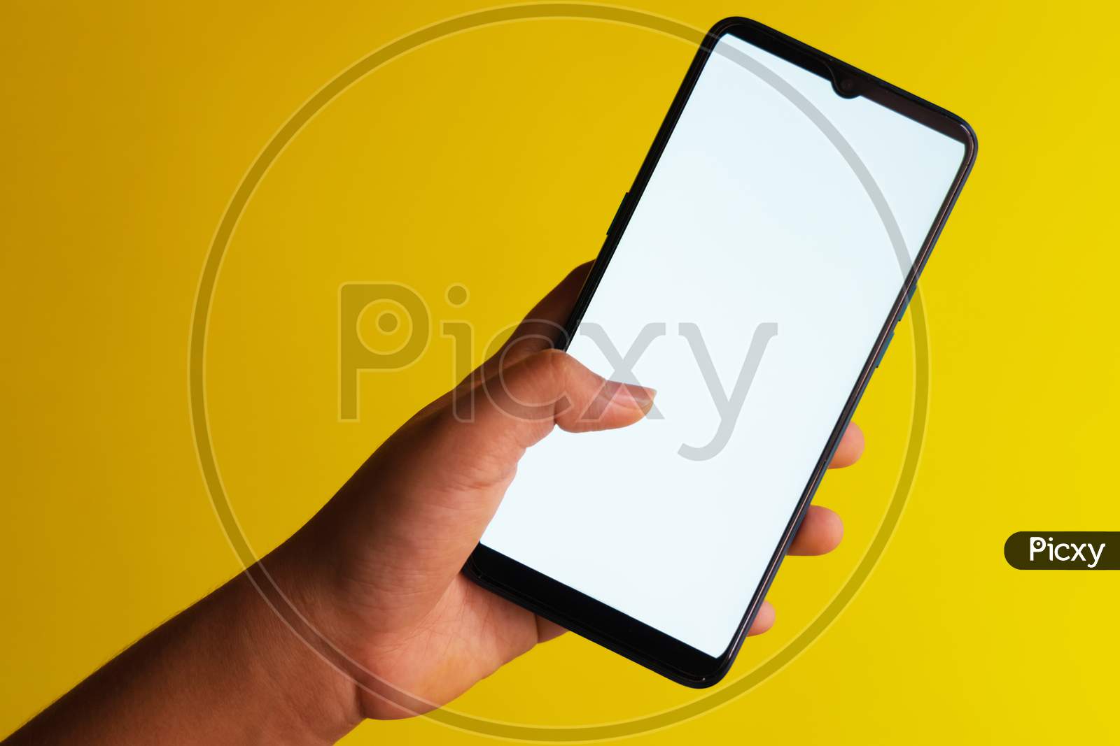 Finger tapping on a smartphone with white screen held against a plain yellow background with copy space