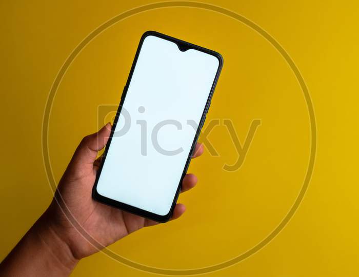 Smart phone with white screen held against a plain yellow background with copy space