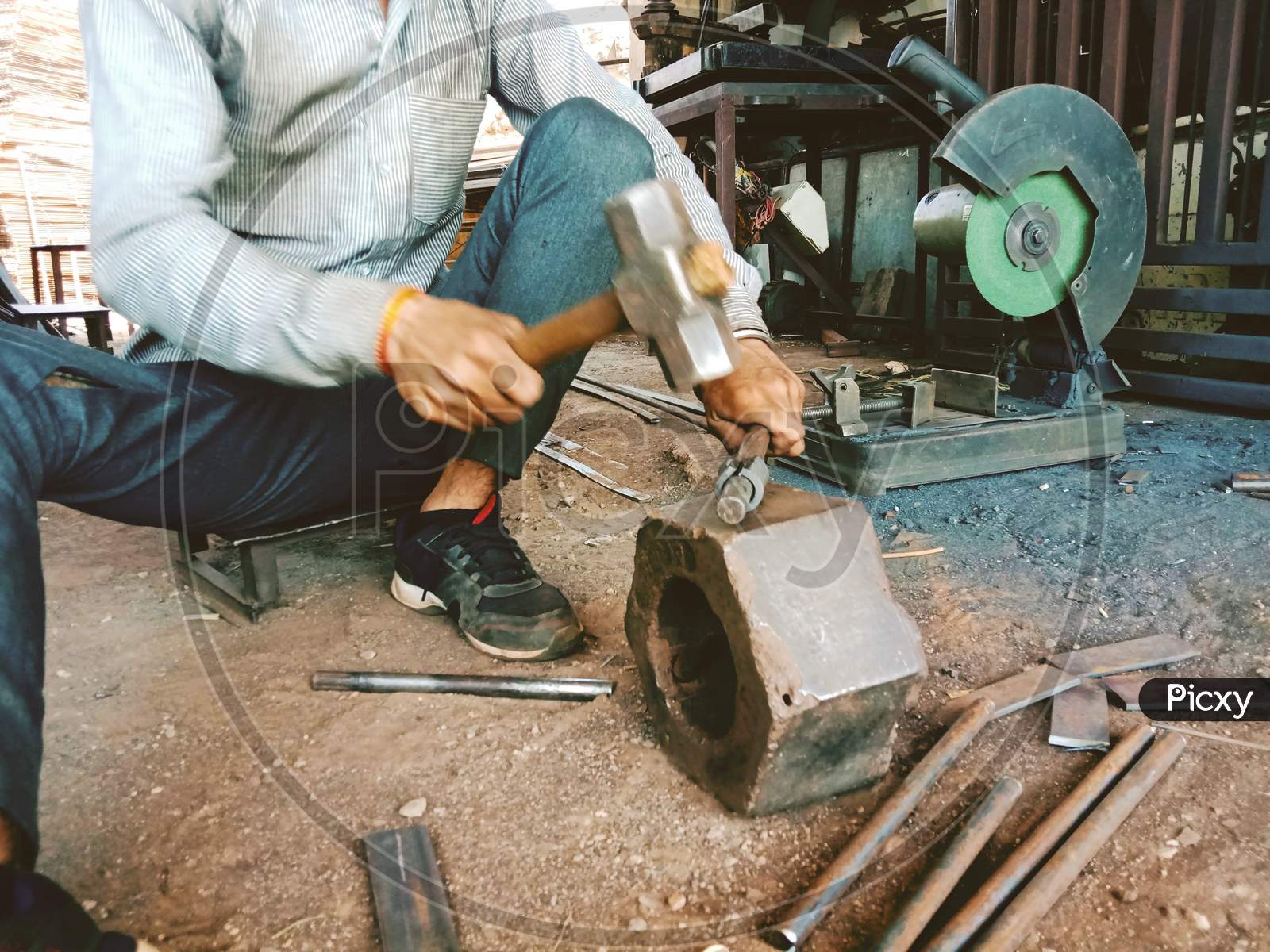Worker Beating Or Hit A Iron Piece To Give A Shape In Iron Workshop With Hammer