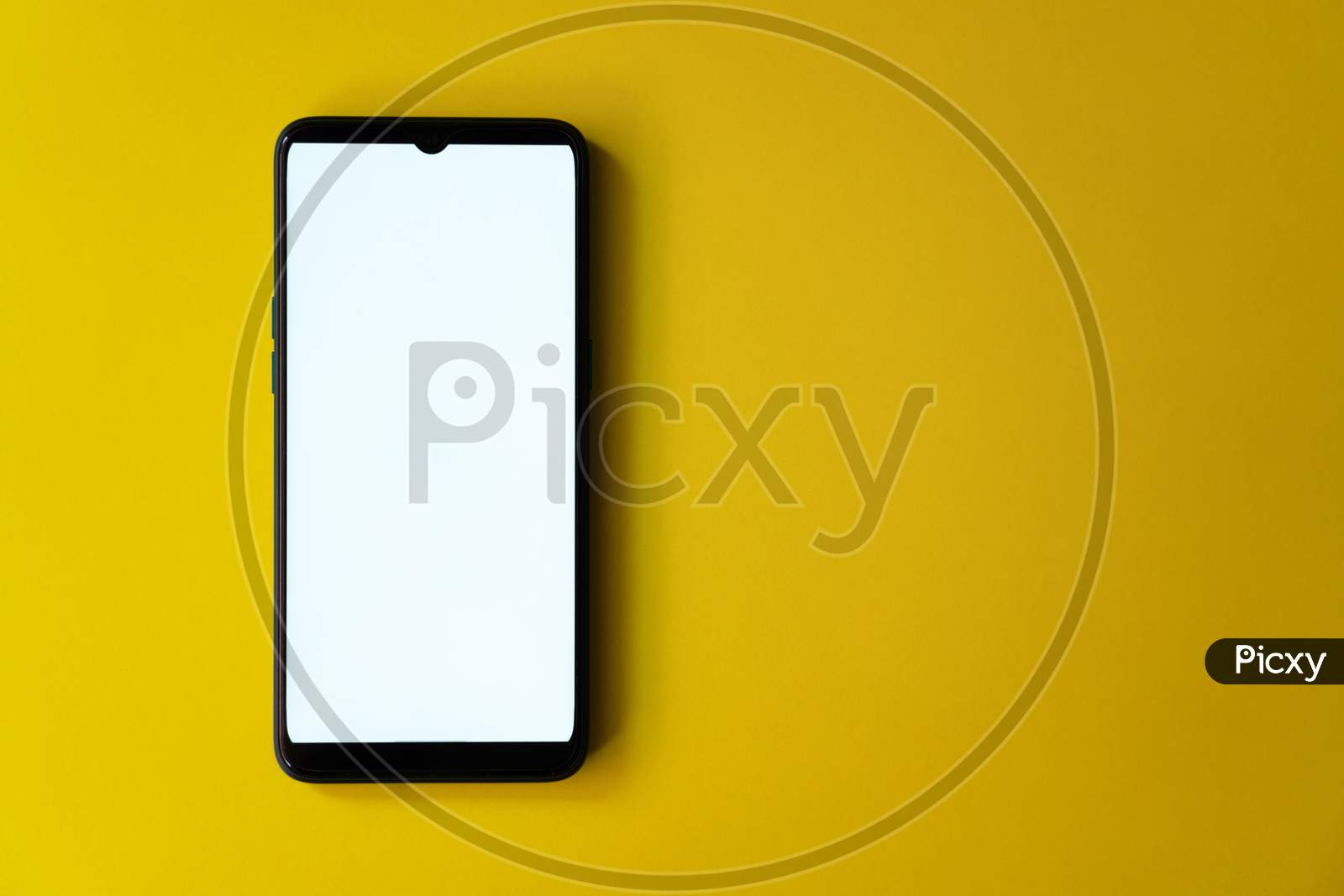 White screen on mobile phone placed on yellow extendable background with copy space